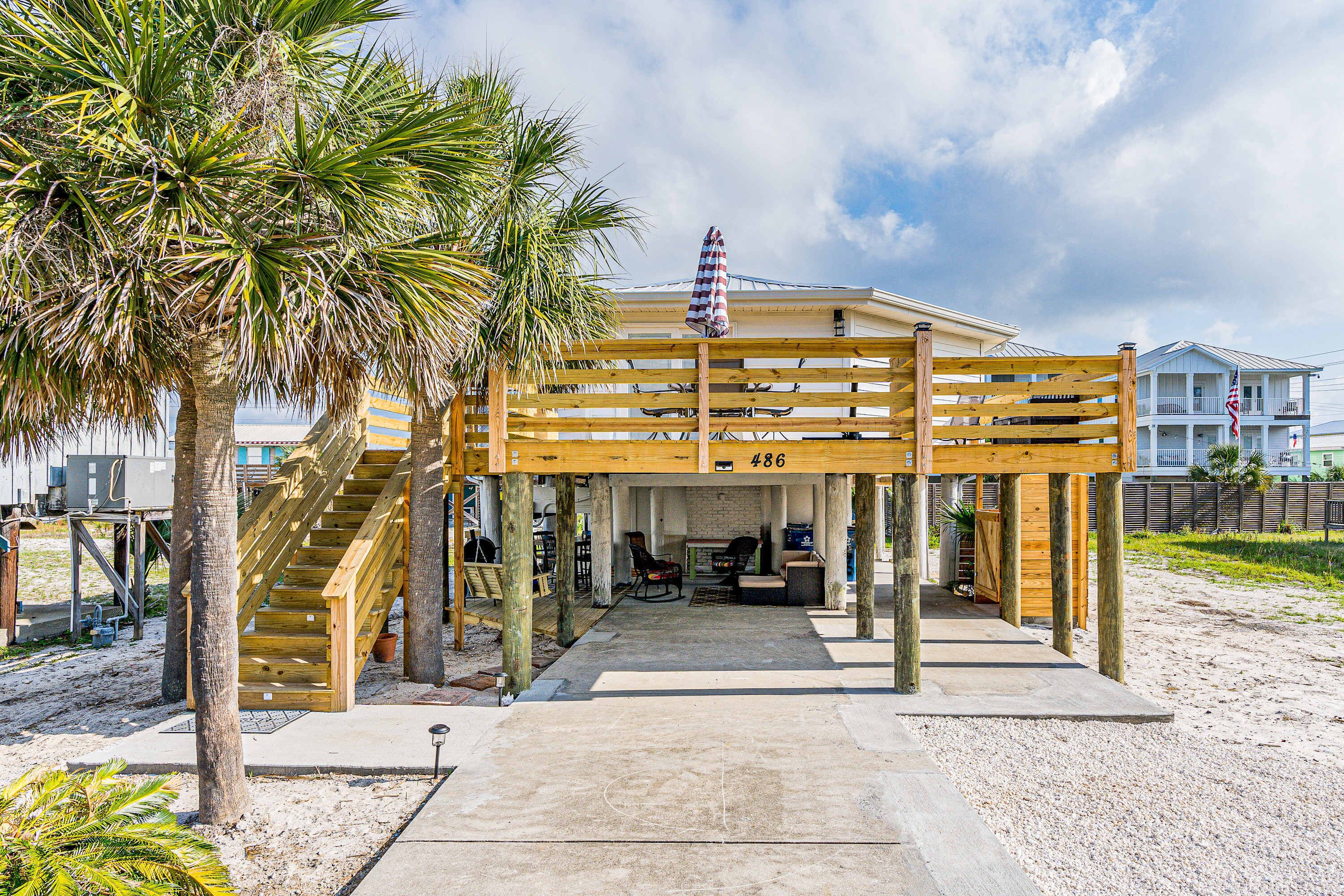 Eine Holzkonstruktion am Strand mit Treppe, überdachtem Sitzbereich und Blick auf das Meer.
