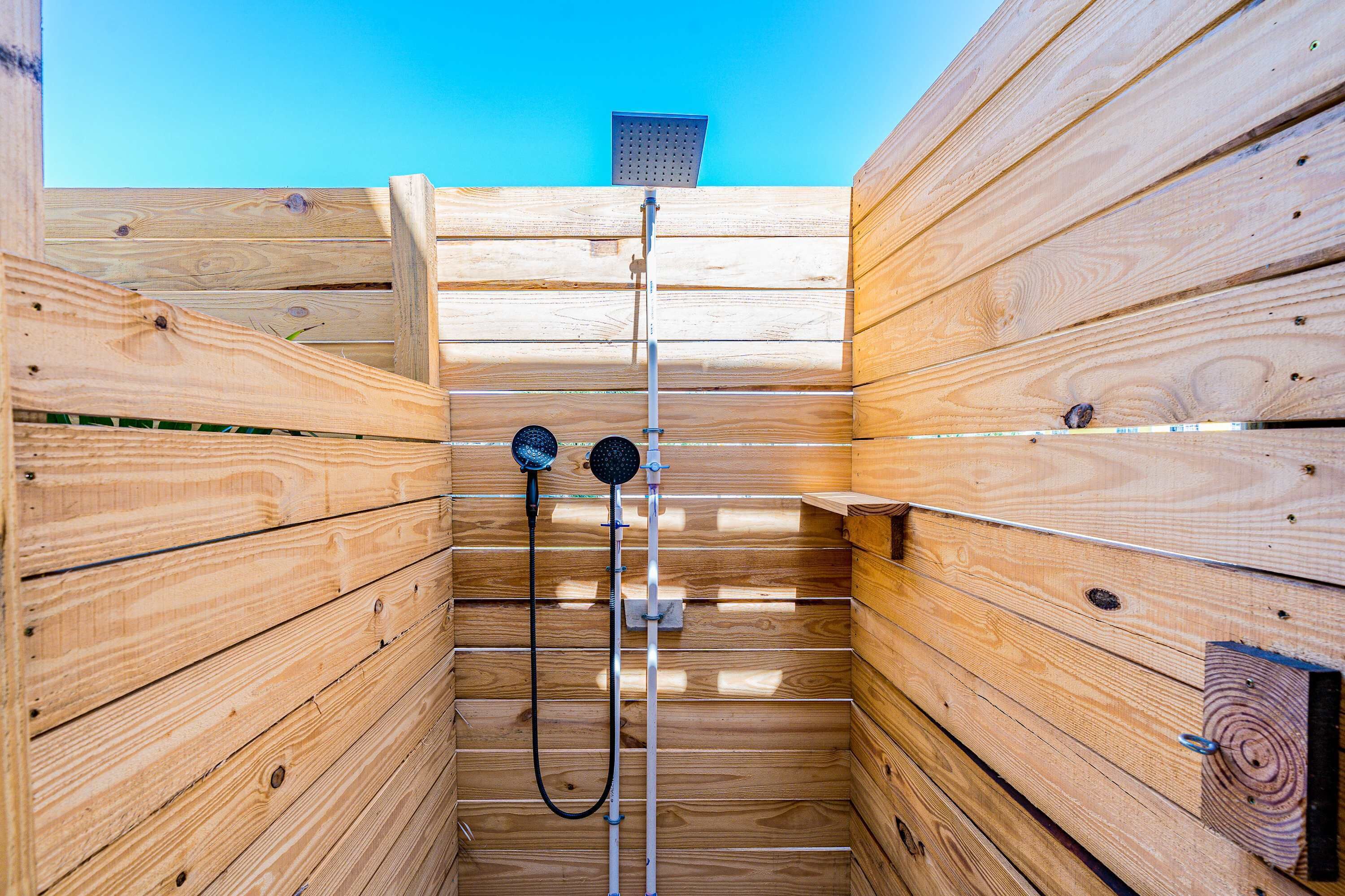 A wooden sauna with a showerhead and a towel rack.