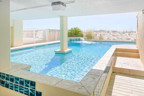 Ein Swimmingpool mit klarem Wasser, einer gefliesten Liegefläche und einem weißen Geländer.