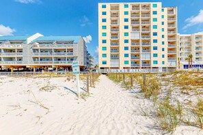 Ein Strandhotel mit mehreren Balkonen, ein Sandstrand davor und ein Schild, das privates Eigentum kennzeichnet.