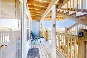 Eine Holzterrasse mit Geländer, ein überdachter Bereich mit Aussicht und eine Sitzgruppe mit Stühlen.