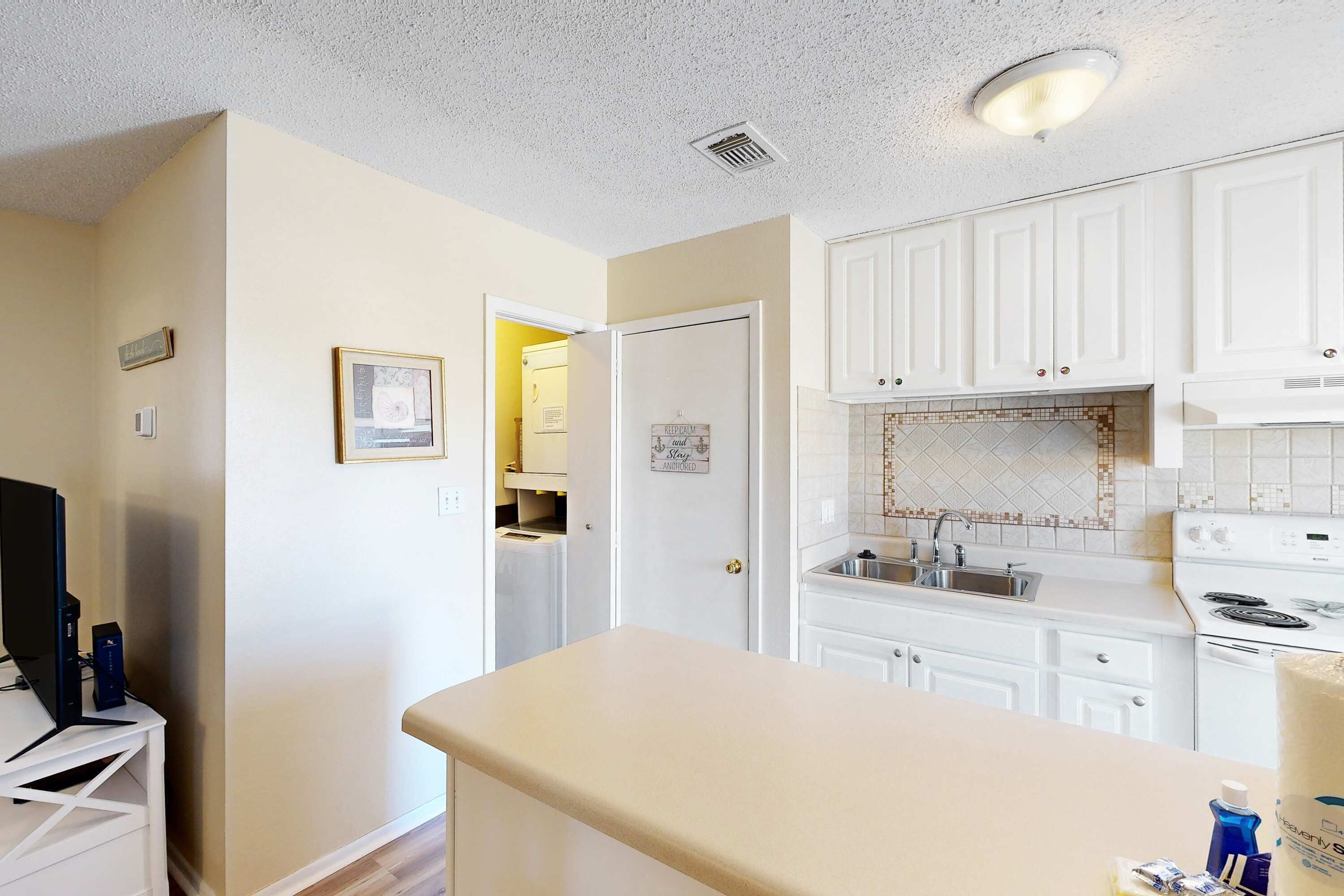 A kitchen with white cabinets, a countertop, a sink, and a stove.
