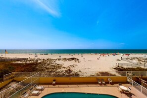 A pool area with lounge chairs and a view of the beach. - 2nd-floor Gulf-front condo with amazing beach views, balcony, outdoor pool & W/D (Gulf Shores)