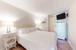 A bedroom with a bed, a nightstand, a dresser, a television mounted on the wall, and a picture on the wall. - 2nd-floor Gulf-front condo with amazing beach views, balcony, outdoor pool & W/D (Gulf Shores)