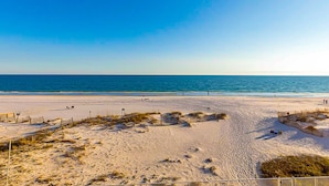 Een strand met een heldere lucht, zandstrand en enkele mensen die wandelen.