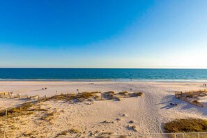 Ein Strand mit blauem Himmel, sandigem Ufer und einigen Spaziergängern.