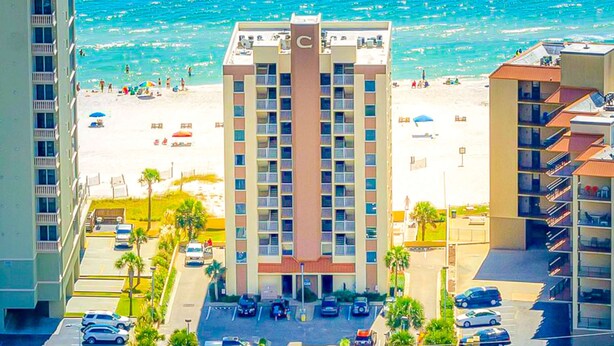 Hotel met een centraal torentje, parkeerplaats en uitzicht op het strand.