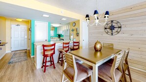 Un comedor con una mesa y sillas de madera, una araña y un adorno de brújula en la pared.