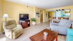Una sala de estar con sofá, televisión, lámpara y mesa de centro.