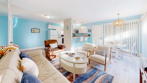 Ein Wohnzimmer mit einer Couch, Sesseln, einem Couchtisch und einem Essbereich mit Tisch und Stühlen.