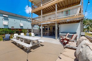 Une terrasse en bois à plusieurs niveaux, dotée d’un espace salon extérieur, d’une zone couverte et d’une porte de garage.