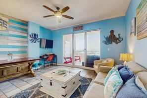 Ein Wohnzimmer mit Deckenventilator, Couch, Fernseher und einem Holztisch.