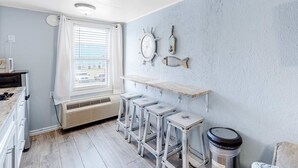 A kitchen with a window, a white refrigerator, a wooden countertop, and a set of bar stools.