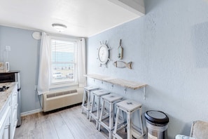 Una cocina con ventana, un refrigerador blanco, una encimera de madera y un juego de taburetes de bar.
