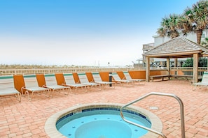 A pool area with lounge chairs, a gazebo, and a view of the beach. - Attractive and Convenient Gulf-Front Home Right on Beach with Shared Pool, Hot Tub (Gulf Shores)