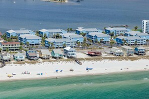 Un hôtel situé sur la côte, avec plusieurs bâtiments bleus, une plage et une jetée.