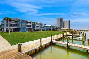 Un hôtel situé au bord de l’eau, doté d’une pelouse verdoyante, d’une jetée en bois et offrant une vue dégagée sur l’eau.