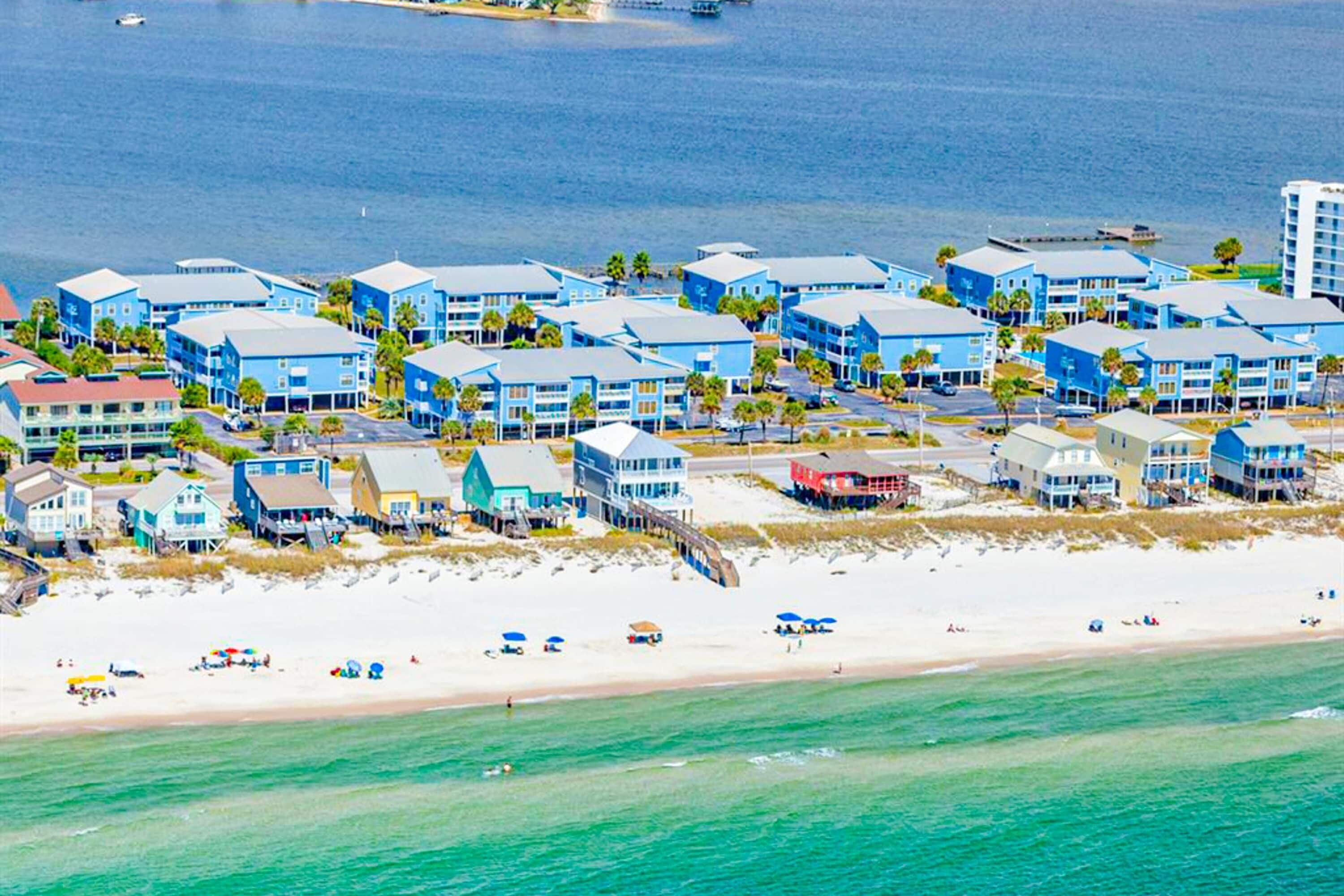 Ein Küstenhotel mit mehreren blauen Gebäuden, einem Strand und einem Steg.