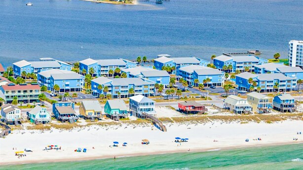 Een kusthotel met meerdere blauwe gebouwen, een strand en een pier.