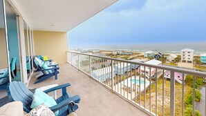 Ein Balkon mit blauen Liegestühlen und Blick auf das Meer und Strandhäuser.