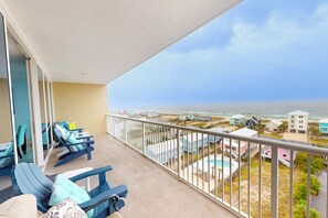A balcony with blue lounge chairs and a view of the ocean and beach houses. - Wonderful Gulf Shores Home with Fantastic Water Views, Free WiFi, Shared Pool,Sauna (Gulf Shores)