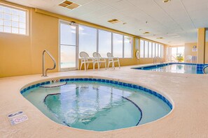 Ein hallenbad mit großen Glaswänden, gefliestem Boden und einigen weißen Stühlen.