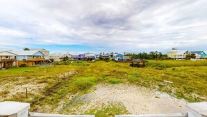 Une zone résidentielle côtière, avec des maisons, un terrain herbeux et un paysage sablonneux en premier plan.