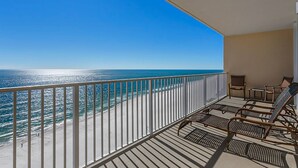Un balcone con vista sull'oceano, arredato con sedie in vimini e un tavolino.