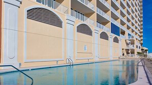 Un albergo con piscina, diversi balconi e un cielo azzurro.
