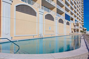 Ein Hotel mit Schwimmbad, mehreren Balkonen und blauem Himmel.