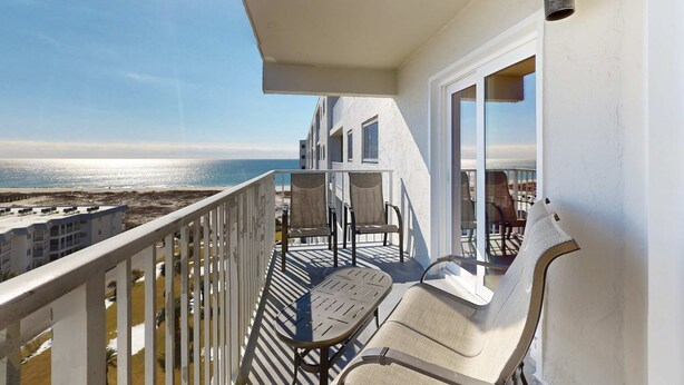 A balcony with a view of the ocean, two chairs, a table, and a railing. - Gulfview condo wbalcony & resort amenities - shared pools, hot tubs, tennis (Gulf Shores)