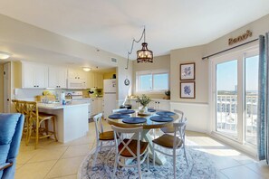 Een moderne keuken met witte kasten, een centraal eiland en een eetgedeelte met een ronde tafel en stoelen.