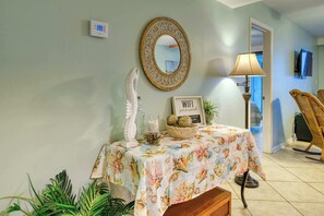 A room with a table covered by a floral tablecloth, a decorative mirror, a lamp, and a sign reading 'WIFI password.' - Waterfront condo with amazing views, beach access & pool/hot tub on-site (Orange Beach)