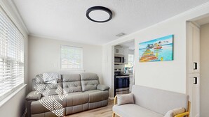 Ein Wohnzimmer mit einer Couch, einem Relaxsessel und einem Gemälde an der Wand.