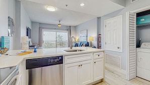 A modern kitchen with a dishwasher, white cabinets, a sink, and a laundry area. - Updated Gulf front condo w/ shared pool, hot tub, and sauna, & beach access (Orange Beach)