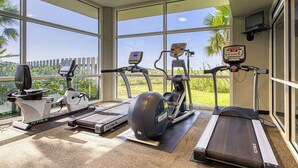 A gym with treadmills, an elliptical, and a stationary bike, large windows, and a view of greenery. - Updated Gulf front condo w/ shared pool, hot tub, and sauna, & beach access (Orange Beach)