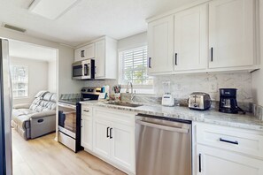 A modern kitchen with white cabinets, a built-in microwave, a toaster, and a coffee maker. - Two charming homes with sparkling water views and close to the beach (Gulf Shores)