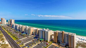 A coastal hotel with multiple floors, a parking lot, and a beach view. - Beachview condo with shared indoor and outdoor pool, beach acces, and WIFI (Gulf Shores)
