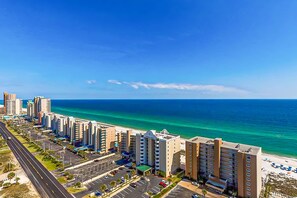 Ein Hotel an der Küste mit mehreren Etagen, einem Parkplatz und Blick auf den Strand.