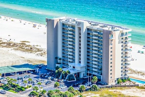 A high-rise hotel with multiple floors, a parking lot, and a beach view. - Amazing Condo in Gulf-Front w/Free WiFi, Shared Pool & Hot Tub, Central AC (Orange Beach)