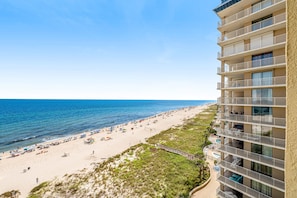 Un hôtel situé en bord de mer, doté de nombreux balcons, d’une plage de sable et offrant une vue dégagée sur l’océan.