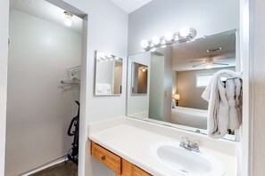 A bathroom with a white sink, vanity, and mirrors with lights.