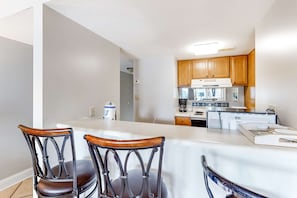 A kitchen with wooden cabinets, a white countertop, and a refrigerator. - Bright resort condo with pool access, cozy patio, plus a washer/dryer (Orange Beach)