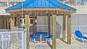 A wooden gazebo with a blue roof, a table with blue benches, and a sign about children's swimwear. - Bright resort condo with pool access, cozy patio, plus a washer/dryer (Orange Beach)
