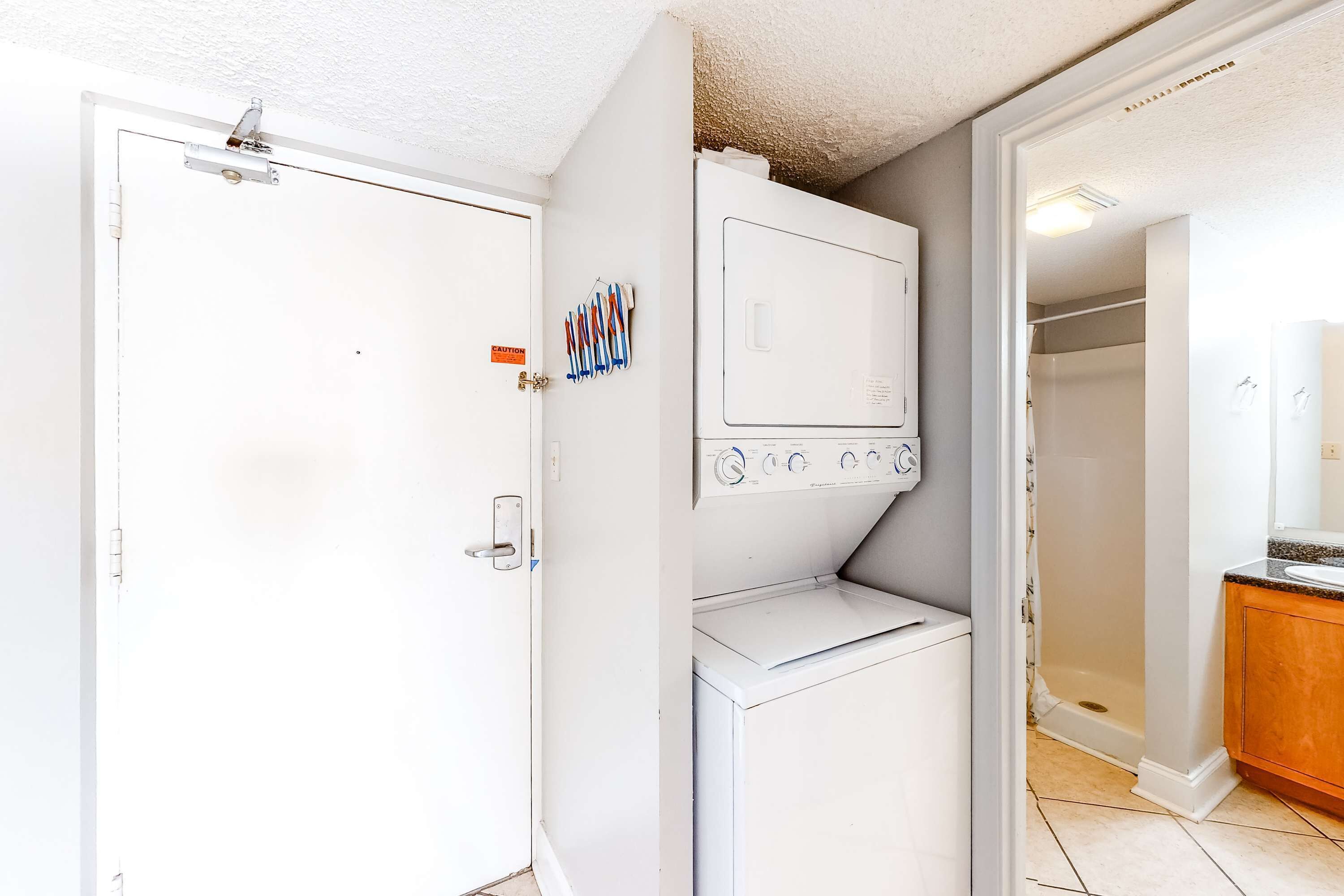 A laundry room with a washer and dryer, a door with a lock, and a shower area visible through an adjacent door.