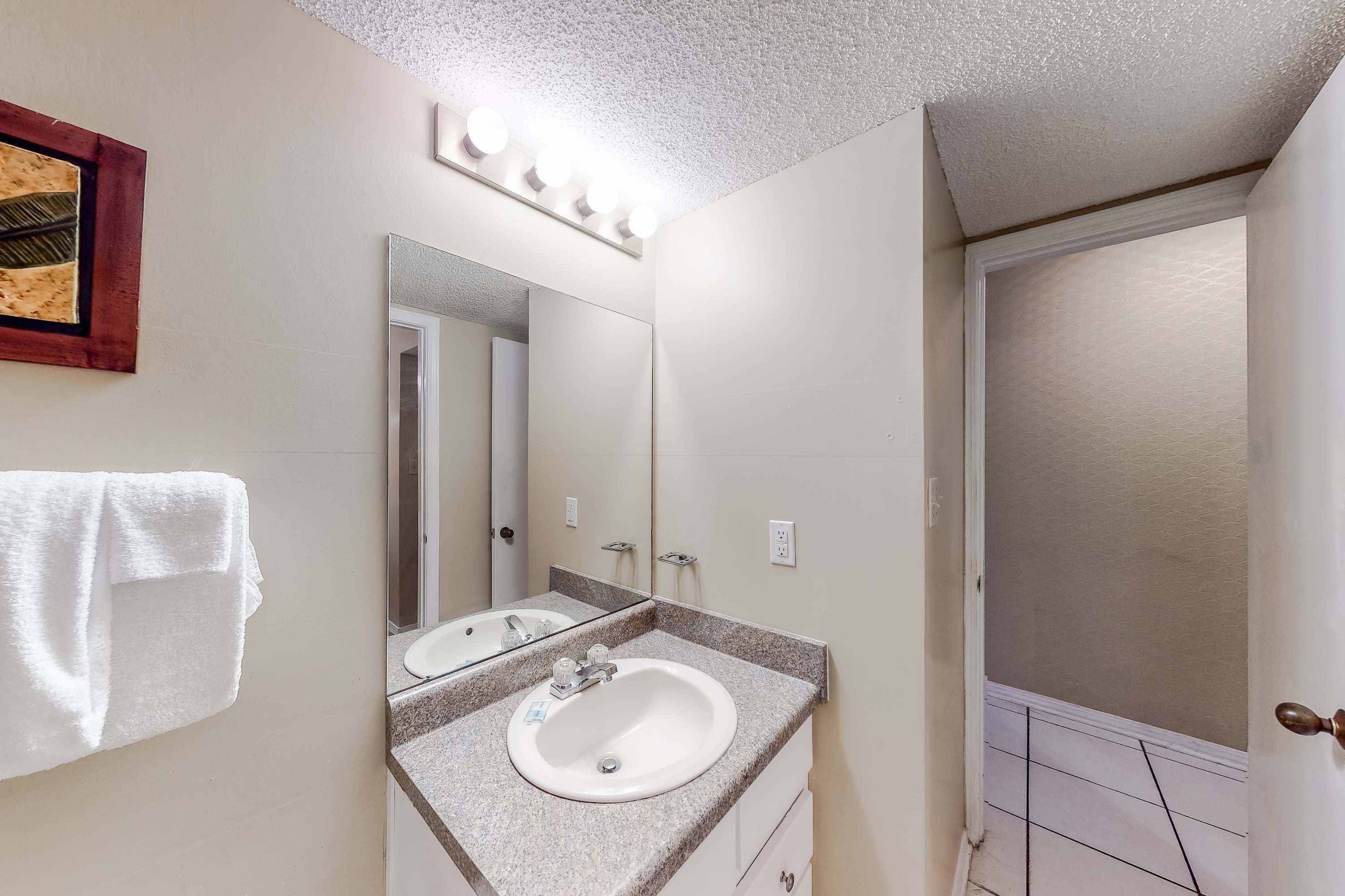 A bathroom with a sink, mirror, and towel rack.