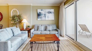 Ein Wohnzimmer mit einer Couch, einem Couchtisch, einer Lampe, einer Pflanze und einem großen abstrakten Gemälde.