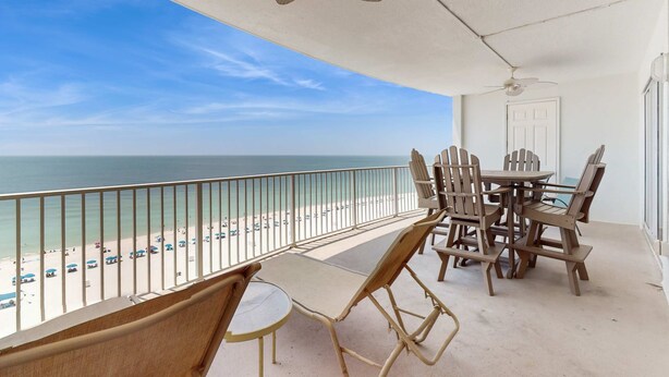 Ein Balkon mit Blick auf den Strand, einem Tisch und Stühlen sowie einem Deckenventilator.