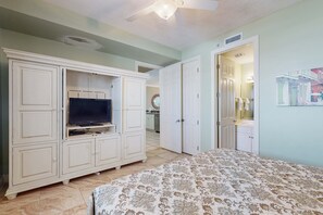 A bedroom with a bed, a TV on a cabinet, and a door leading to a bathroom. - 9th-floor, Gulf-front condo with balcony, pools, hot tubs, gym & beach access (Orange Beach)