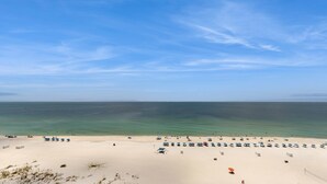 Ein Strand mit blauem Himmel, ruhiger See und mehreren Reihen von Strandsonnenschirmen.